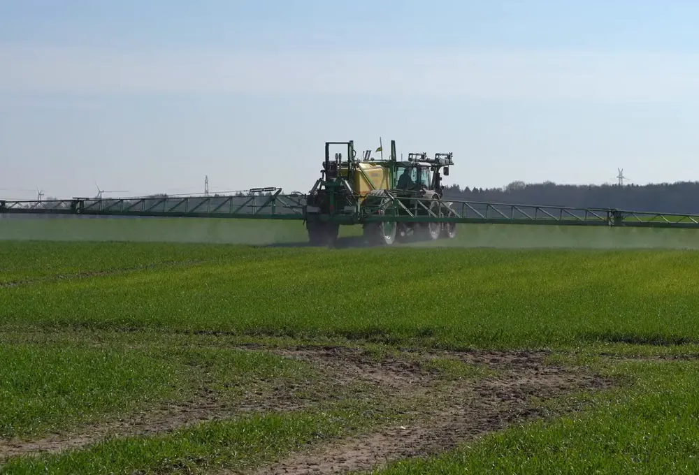 Tractor con barra pulverizadora tratando un cultivo